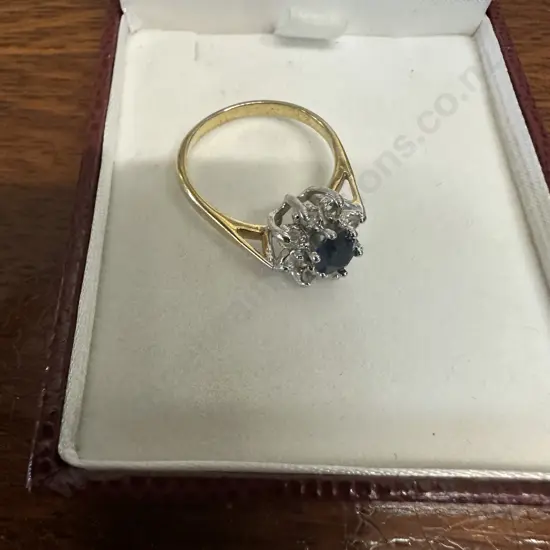 Gold Ring With large Blue Stone Surrounded By Smaller Clear Stones