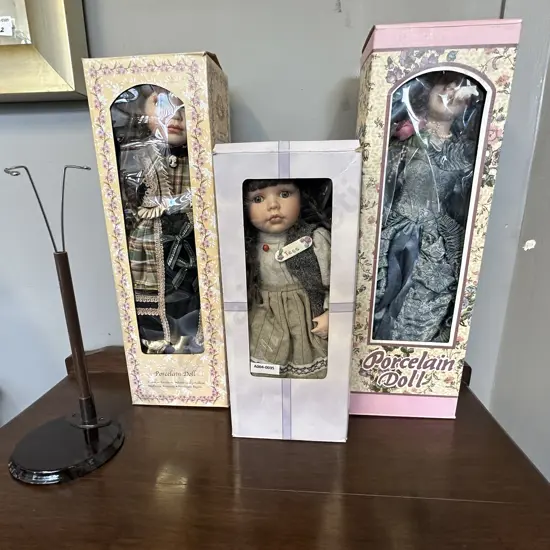 Three Boxed Porcelain Dolls With a Stand